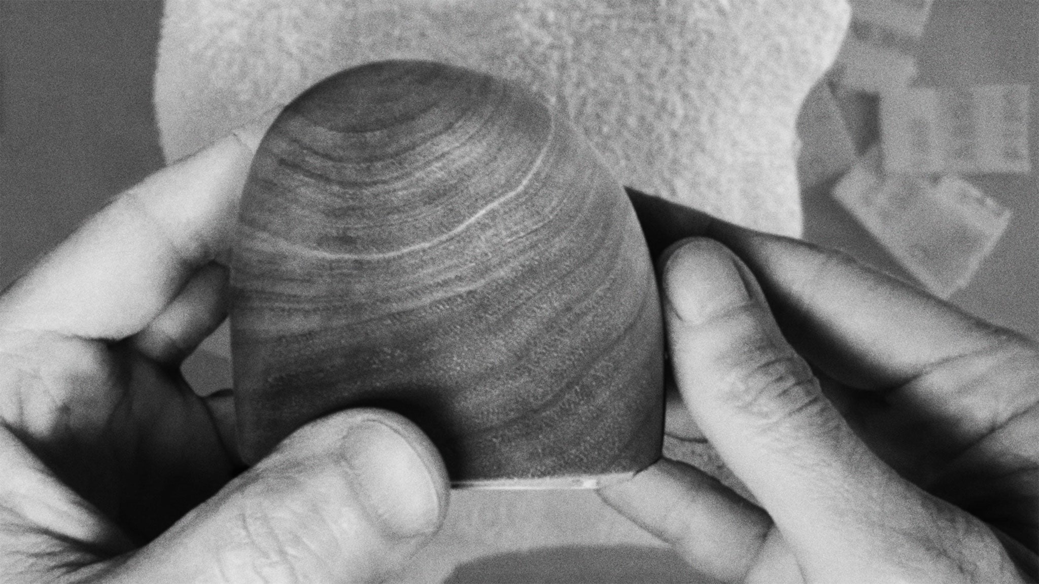 Black & white photograph of hands holding the work in progress of a wood sculpture