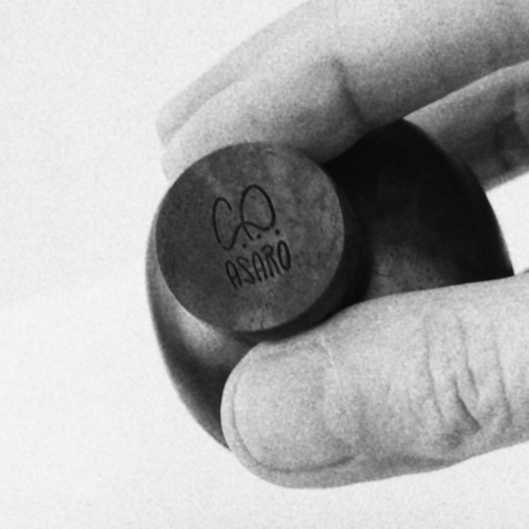 Black and white video clip in 1:1 of hand showing detailed and polished mid century style wood sculptures with artist signature