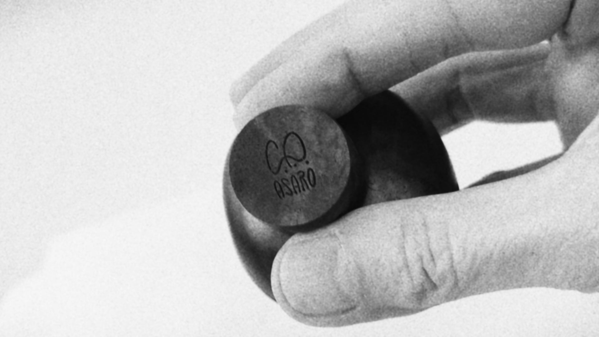 Black and white clip of hand showing detailed and polished mid century style wood sculptures with artist signature.