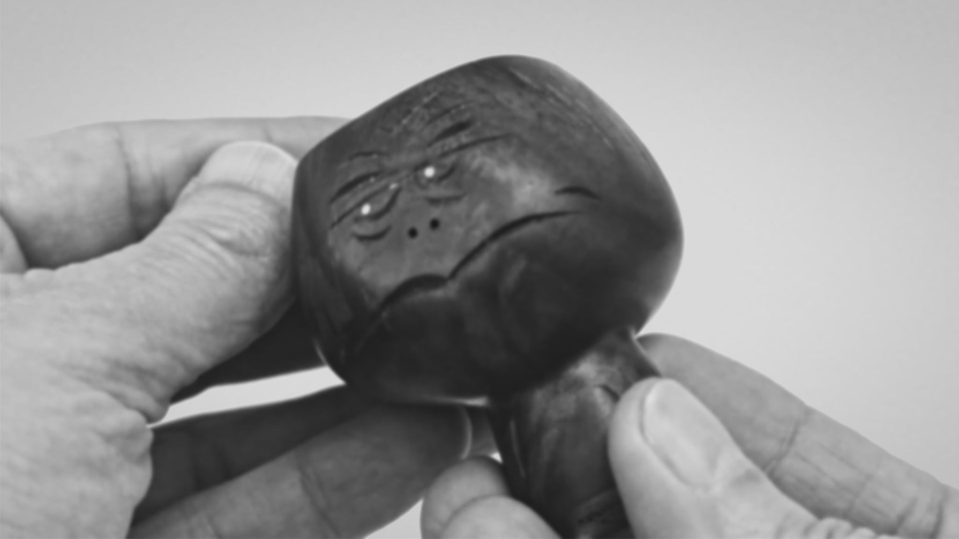 Black and white video clip of hands showing black walnut wood sculpture of abstracted head figure mid-century style about 8cm high