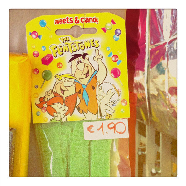 Curio & Co. looks at Flintstones brand candy and merchandise. Photograph of Flintstones candy with price tag in euro. Curio and Co. www.curioandco.com