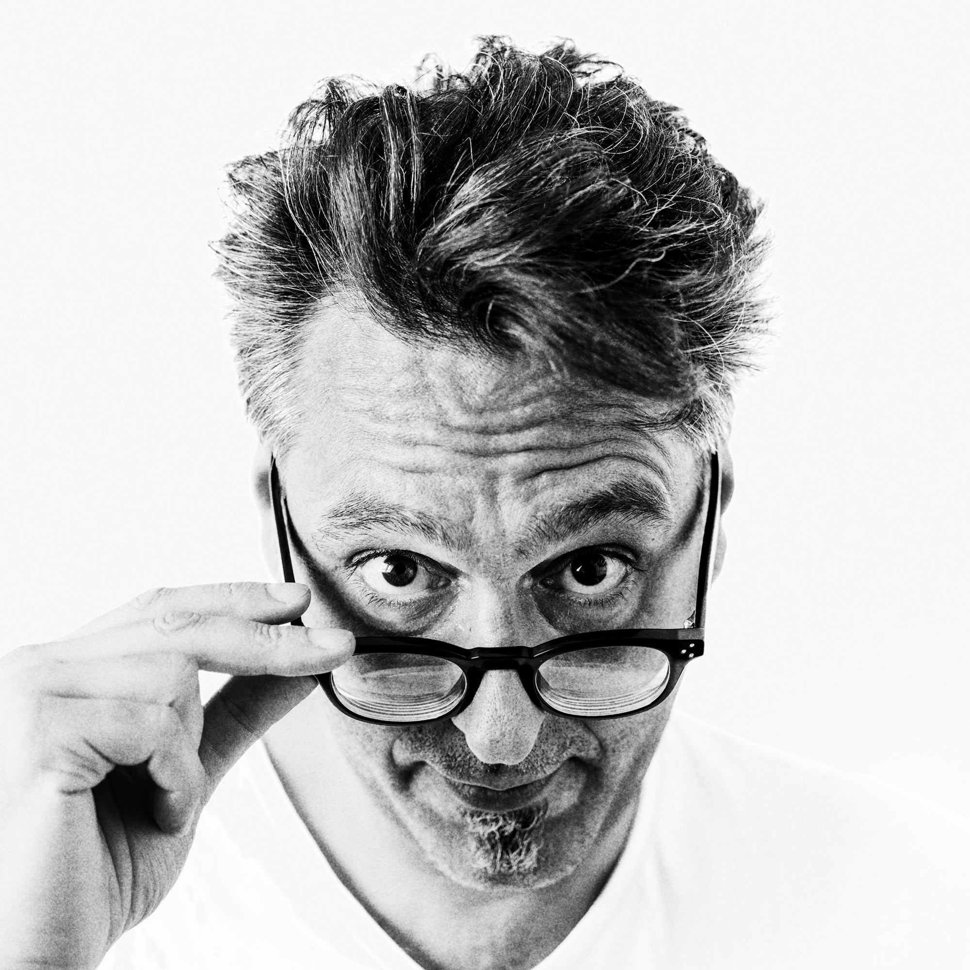 Portrait of Cesare Asaro in black and white looking over glasses on white back ground
