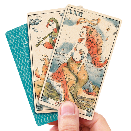 Hand holding 3 tarot cards featuring a mermaid with red hair the fool and the card's back