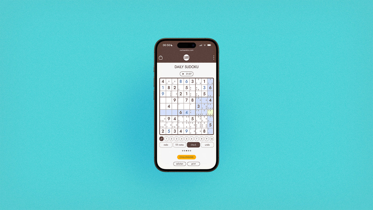 iPhone 16 with screen on curioandco.com's interactive daily sudoku puzzle being solved. Photo on aqua background