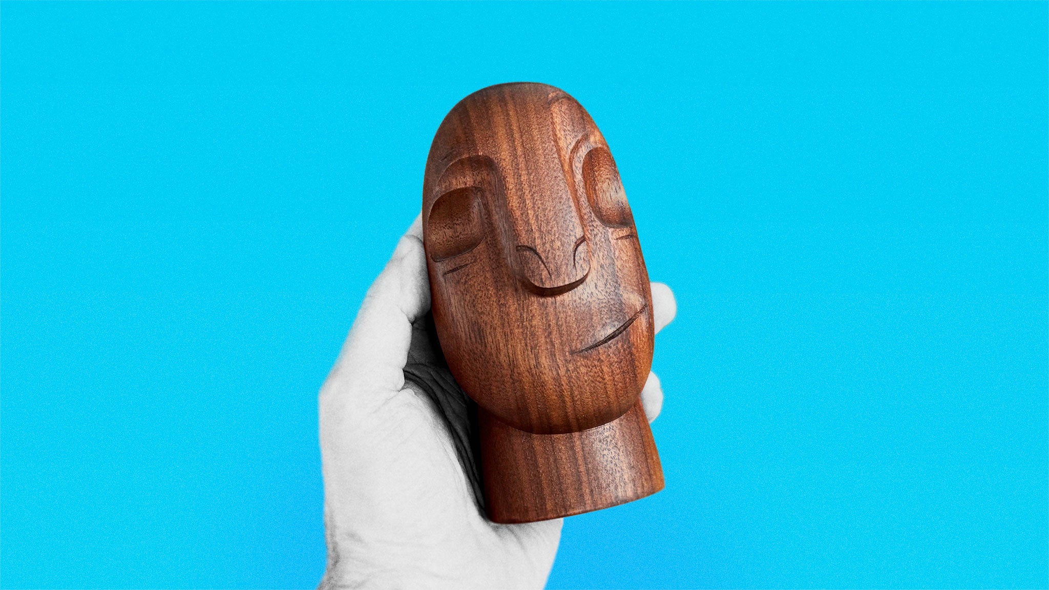 Timeless Mid-Century sculpture in black walnut about 16 cm high of smiling rounded shaped stylized head held in hand on azure background