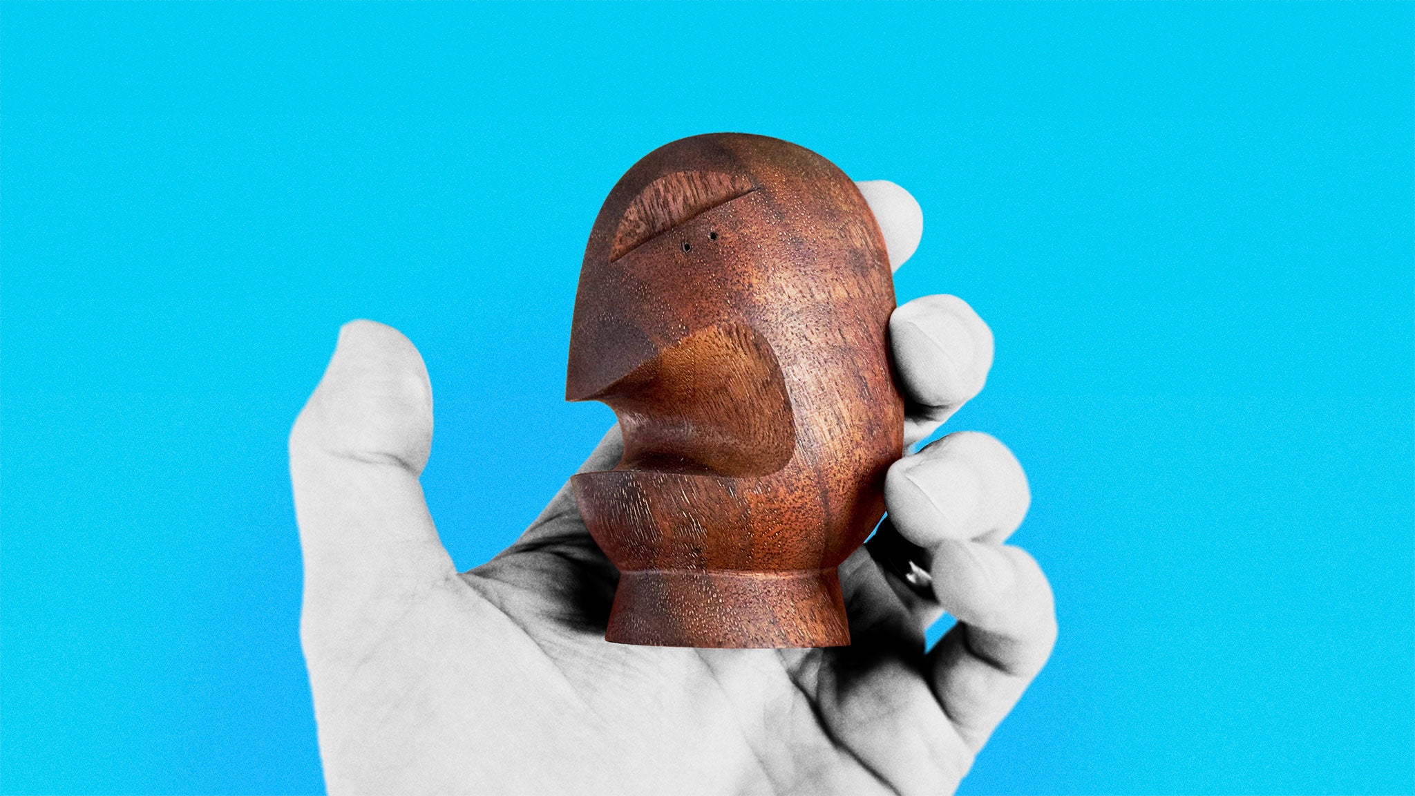 Timeless Mid-Century sculpture in black walnut about 11 cm high of rounded shaped stylized head with  open mouth held in hand on azure background
