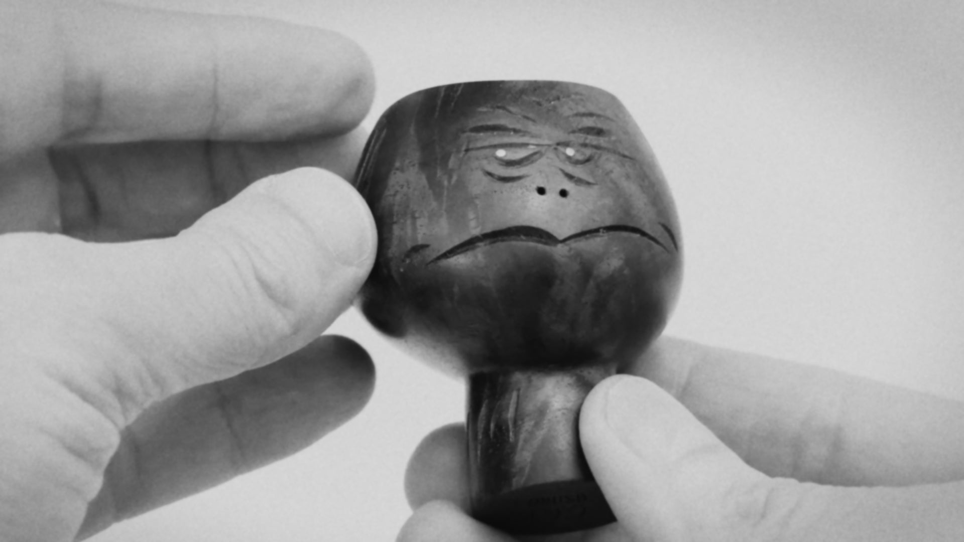 Black and white video clip of hands showing black walnut wood sculpture of  abstracted head figure mid-century style about 8cm high