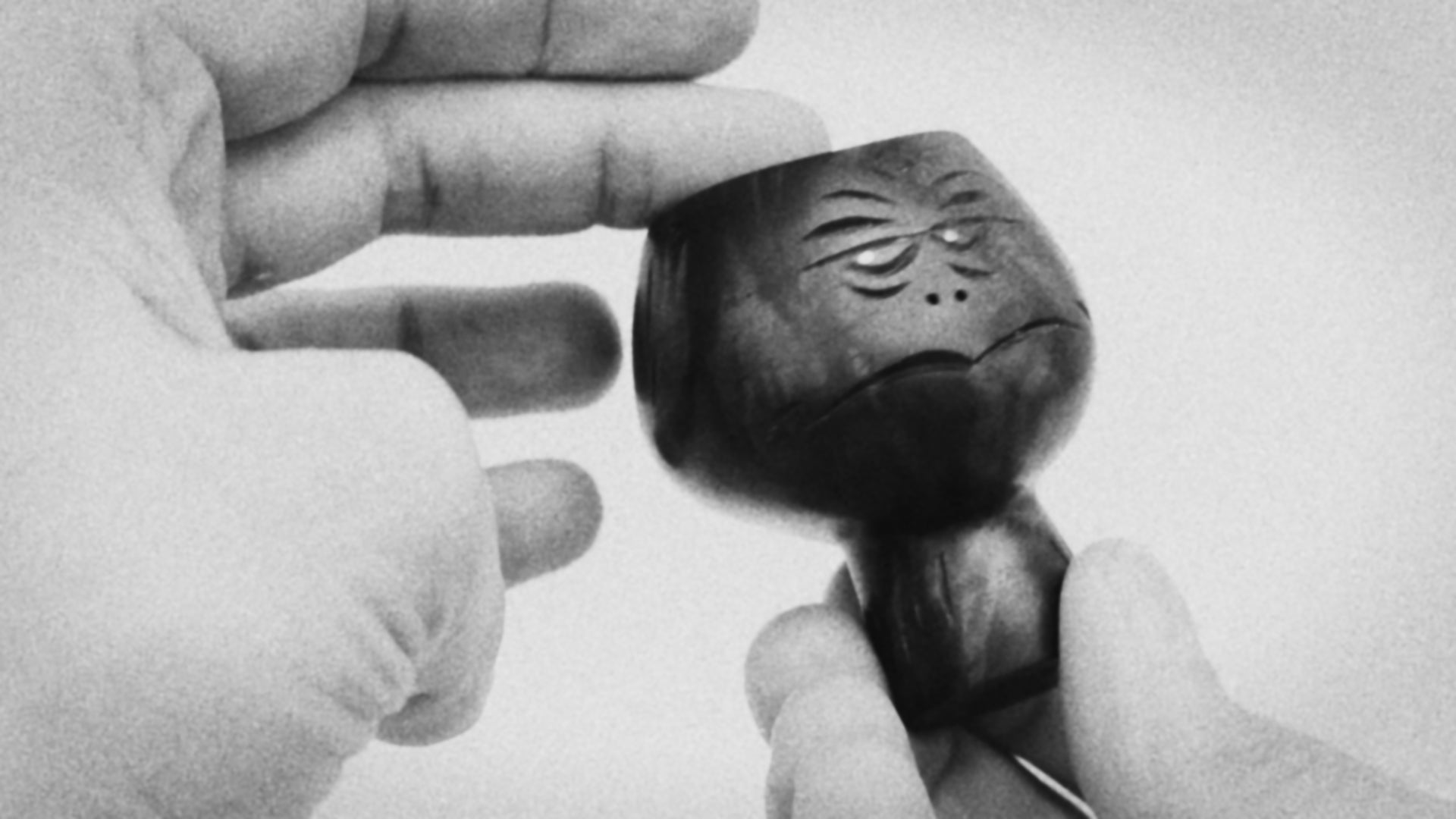 Black and white video clip of hands showing black walnut wood sculpture of  abstracted head figure mid-century style about 8cm high